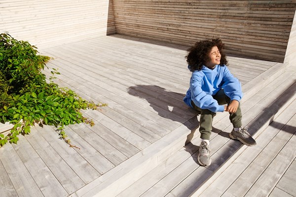 A child sitting in the sun on a sundeck